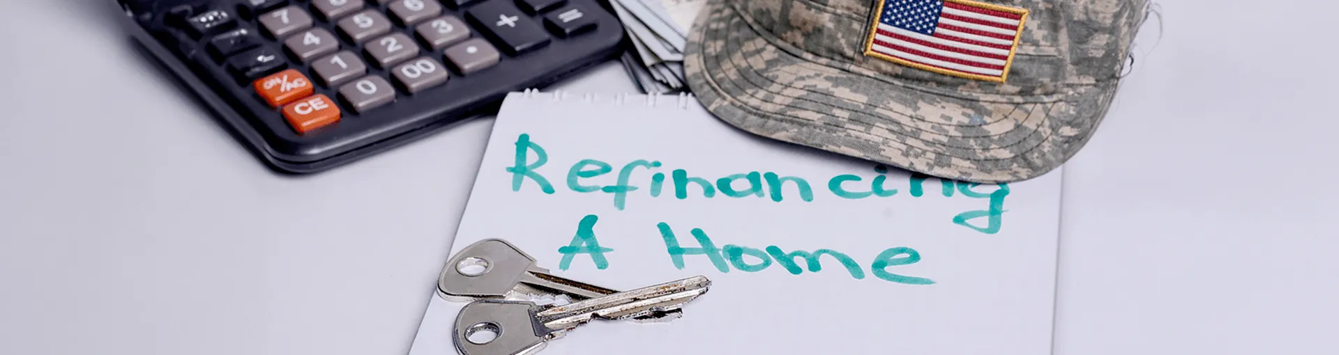 Keys, a hat, a calculator, and a note that says "refinance a home"