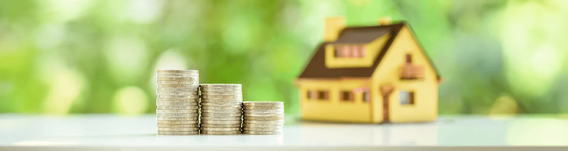 A yellow and brown house with coins stacked in front of it