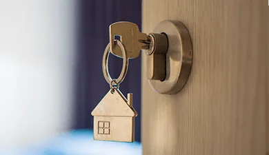 A key with a house-shaped keychain in a lock