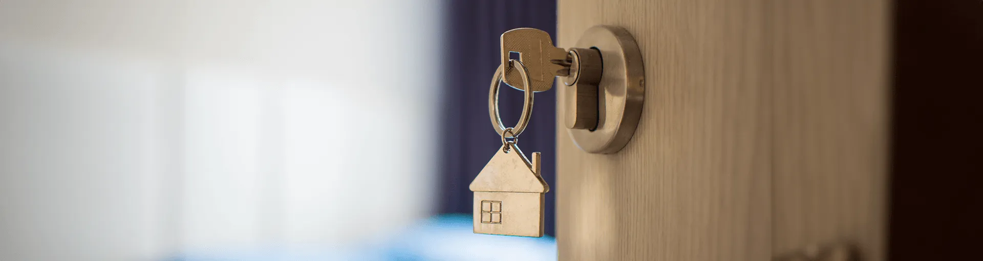 A key with a house-shaped keychain in a lock