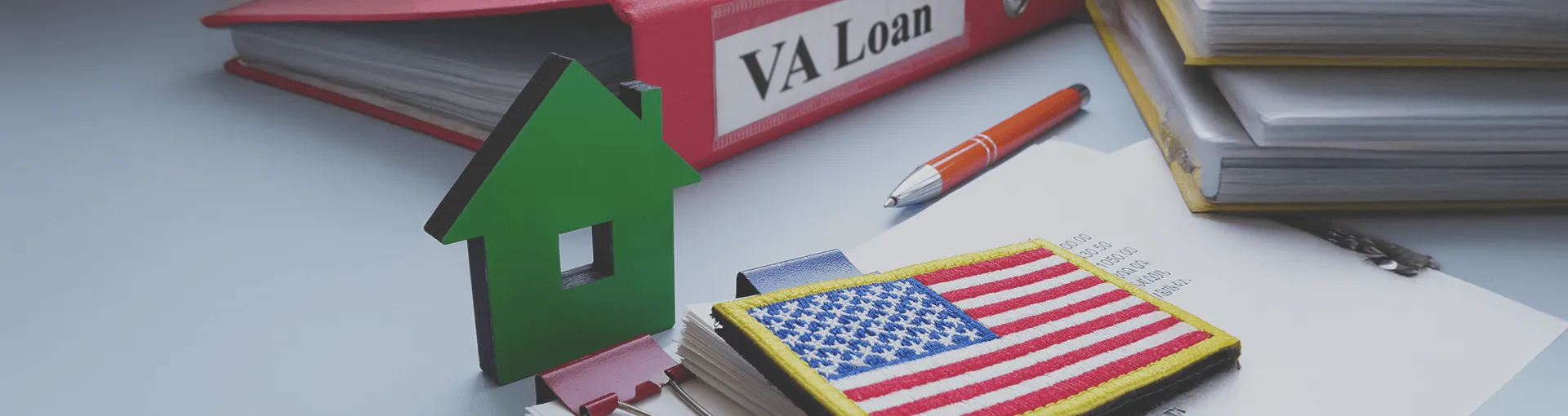 Office supplies on a desk and a binder that says VA Loan
