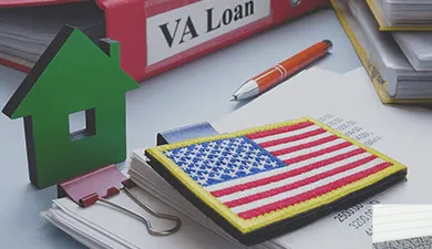Office supplies on a desk and a binder that says VA Loan